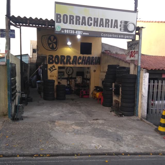 Fachada amarela da borracharia, com letreiro e pilhas de pneus