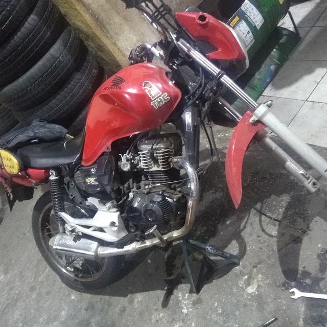 Moto Honda vermelha sem a roda dianteira, em reparo